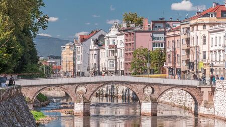 View of the Latin bridge timelapse, one of the oldest bridges of Bosnia and Herzegovina, runs through the Milyacka River in Sarajevo at sunny dayの写真素材