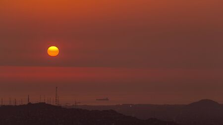 Aerial view of the Pacific ocean during sunset timelapse from Cerro San Cristobal, Lima. Orange sky with sunの写真素材