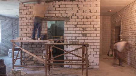 Builders laying brick walls inside appartment with professional tools timelapse. Workmen at work, bricklayers building wall, contractor and worker. Building materials aroundの写真素材
