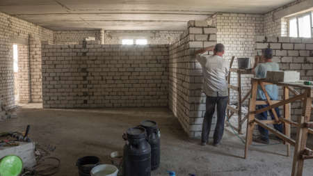 Builders laying brick walls inside appartment with professional tools timelapse. Workmen at work, bricklayers building wall, contractor and worker. Building materials aroundの写真素材
