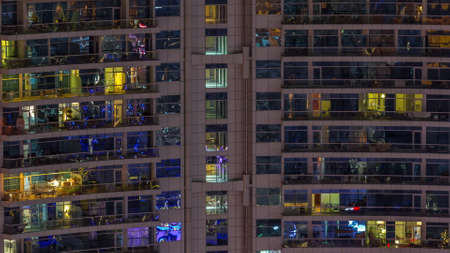 Night view of exterior apartment colorful building timelapse. High rise skyscraper with glowing...