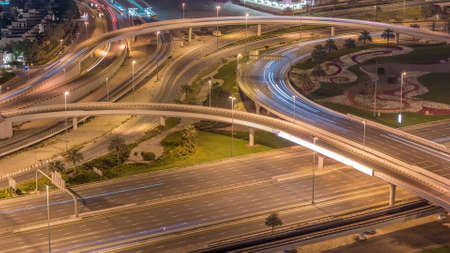 Aerial view on Dubai Marina with big highway intersection night timelapse and skyscrapers around,...