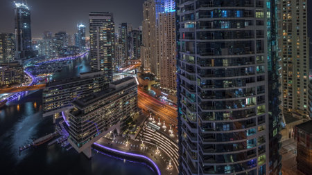 Aerial view to Dubai marina skyscrapers around canal with floating boats night timelapseの写真素材