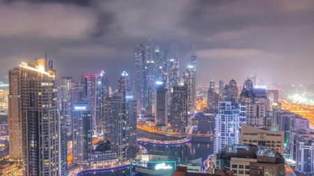 View of various skyscrapers in tallest recidential block in Dubai Marina aerial all night timelapseの写真素材