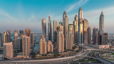 Dubai Marina highway intersection spaghetti junction night to day transition. Illuminated tallest skyscrapers on a background. Aerial top view from JLT district before sunriseの写真素材