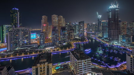 Panorama showing Dubai Marina skyscrapers and JBR district with luxury buildings and resorts aerial night. Illuminated waterfront and boats floating in canalの写真素材
