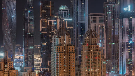 Skyscrapers of Dubai Marina with illuminated blinking windows on highest residential buildings during all night timelapse. Aerial top view from JLT districtの写真素材