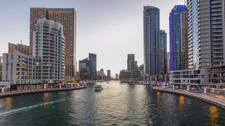Dubai Marina waterfront with towers and yachts from bridge in Dubai day to night transition timelapse, United Arab Emirates. District with artificial canal after sunsetの写真素材
