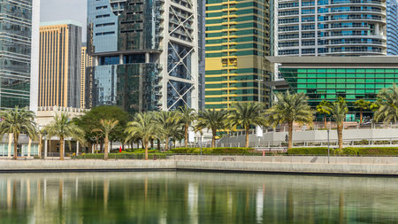 Timelapse view on skyscrapers at waterfront. Residential buildings in Jumeirah Lake Towers reflected in water in Dubai, UAE. View with blue cloudy sky from waterfrontの写真素材