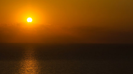Sunset timelapse view: yellow bright sun disc on natural orange sky background. Sunset idea concept. Summer cloudy sky landscape with sun beams and rays of lightの写真素材