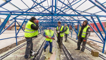 Tram rails at the stage of their integration into concrete plates on the road. Workers make a mix of...