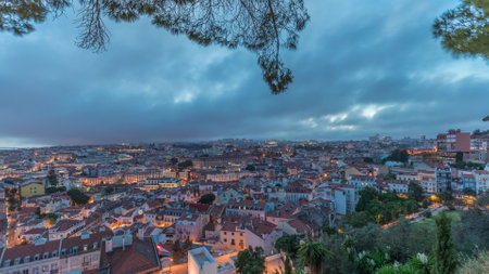 Panorama showing aerial cityscape day to night transition from Miradouro da Graca viewing point in Lisbon city after sunsetの写真素材