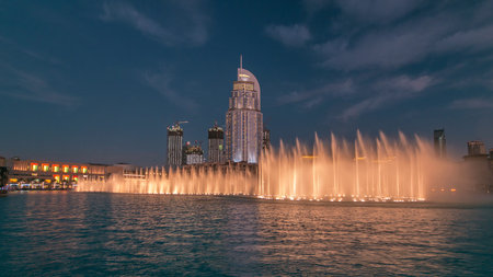 The Dancing Fountain of Dubai and lake day to night timelapse at dusk in Dubai, UAE.の写真素材