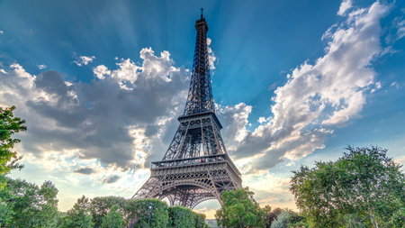 The Eiffel tower with warm rays of light in clouds during sunset timelapse hyperlapse.