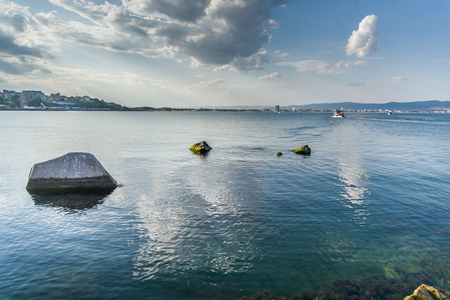 Clear blue water of Ohrid lake,with protruding rocks and fluffy clouds in the background,の写真素材