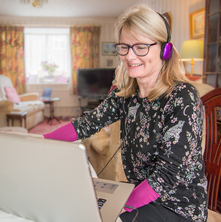 A woman working at home,online with her computer looking at her monitor screen with interest.の写真素材