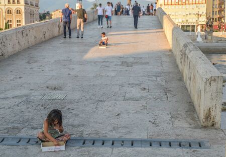 SKOPJE,NORTH MACEDONIA/AUGUST 22 2018:Young children sit on Stone Bridge asking for money from passers by.Skopje,2018.のeditorial素材