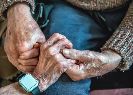 Clasping their old hands together,still in love in their 90's,together,both living and sleeping in the living room downstairs due to their ill health and looked after by family and carers.の写真素材