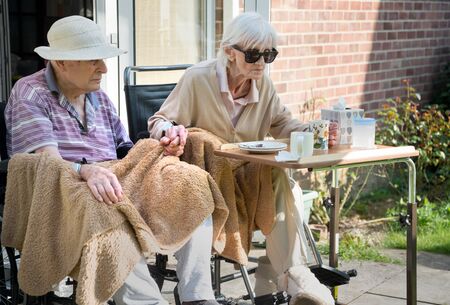 Husband and wife in their 90s still in love and the wife has early stage dementia.Natural and unposed in their back garden during springtime.