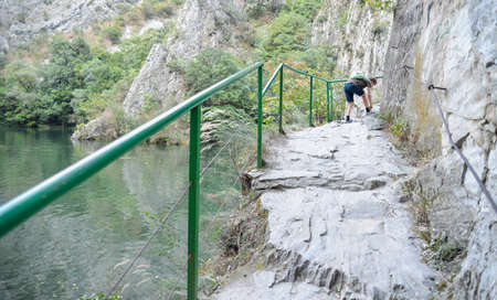 At Matka Canyon,near Skopje a hiker ties his shoelace.Visitors can walk the pathway running next to the river Treska and calm waters of Matka lake.のeditorial素材