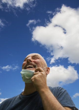 Thankful and joyful,removes his mask,breathing in the fresh air looking up to the sky.Corona virus restrictions are eased and he no longer always needs a face mask and free to enjoy life once again.の写真素材