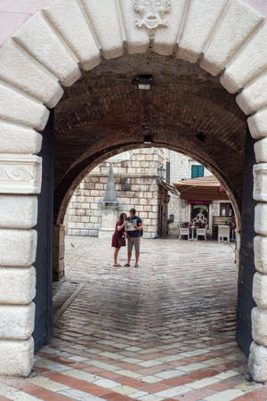 Two people study a tourist map while standing in the middle of the Main square of Kotor,in front of the archway leading into Old Town in the morning.のeditorial素材