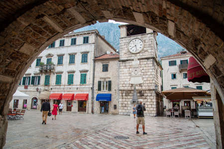 View of the main square and old clock tower from under the archway of the Sea Gate leading into Old Town Kotor.のeditorial素材