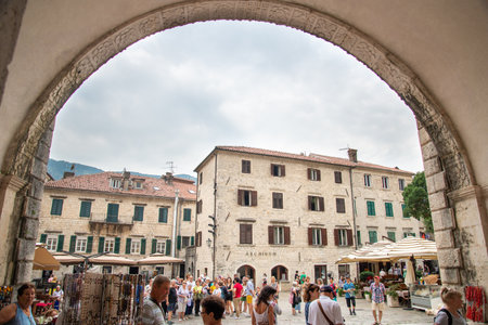 Kotor main square as seen through the archway of the Sea Gate,surrounded by ancient medieval buildings,resaurants and tourist shops.のeditorial素材