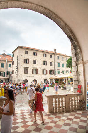 Kotor main square as seen through the archway of the Sea Gate,surrounded by ancient medieval buildings,resaurants and tourist shops.のeditorial素材