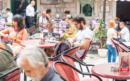 Customers sitting outside a restaurant enjoy relaxing with coffees and refreshments and take in the peaceful atmosphere of the historical old town in the mid afternoon.のeditorial素材
