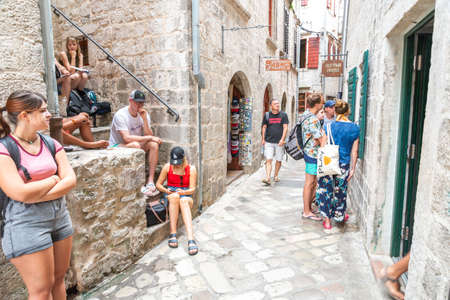 Tourists relax and stroll along an ancient narrow street in Old Town area of Kotor in the afternoon.のeditorial素材