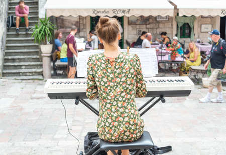Classical pianist performs for tourists in a main square in Old Town, Kotor,Montenegro.Playing her electric keyboard while surrounded by cafes and restaurants with tourists seated around.のeditorial素材