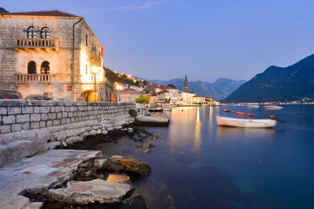 At dusk by the waters of Kotor Bay as boats move gently on the tranquil sea during late summer.の写真素材