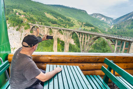 The travel photographer rests at a log cabin cafe,in early Autumn,overlooking the deep gorge and river below with beautiful panoramic views.の写真素材
