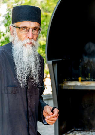 Danilovgrad Municipality, Montenegro-September 13th 2019: At Ostrog monastery a man in traditional orthodox monk's dress,stands by the church entrance,in the shade of a hot summer's afternoon.のeditorial素材