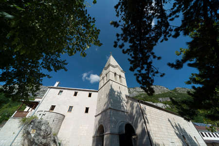 Low angle view of the bell tower,made of white stone blocks,pointing towards blue sky in bright...