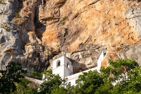 Looking up at the ancient monastery and most popular pilgrimage site, from below the trees towards the large rock that it has been carved into,and clear blue sky,on a sunny summer day.の写真素材