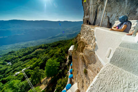 Ostrog,Montenegro-September 13 2019: Visitors to the monastery overlook the Zeta valley and Bjelopavlici plain,from a high balcony,on a sunny afternoon, at Montenegro's most popular pilgrimage site.のeditorial素材
