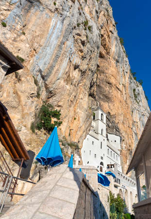 Low wide angle view of higher main monastery.A Serbian orthodox building with arched architecture ,high vertical cliffs high above and blue sunny summer sky.のeditorial素材