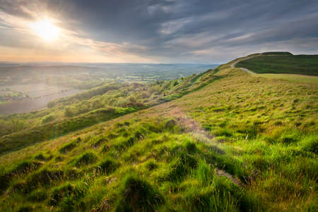 The summer sun rising over Worcestershire countryside,shining low angled sunlight across lush grass...