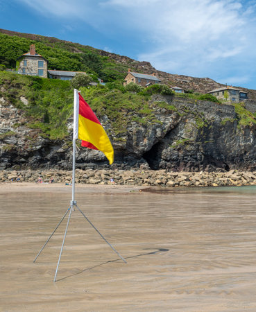 St.Agnes,Cornwall,England,UK-July 22: A sea safety flag,erected on a tripod by members of the RNLI,shows colours indicating recommended swimming area with lifeguards on duty,on a fine summer day.の写真素材