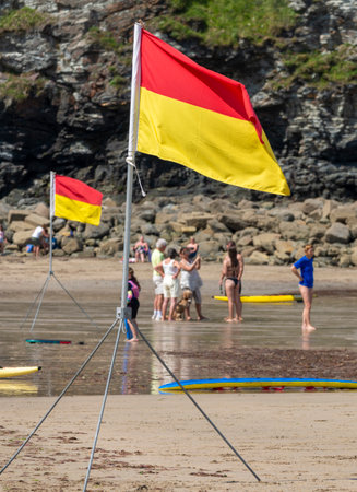 St.Agnes,Cornwall,England,UK-July 22: A sea safety flag,erected on a tripod by members of the RNLI,shows colours indicating recommended swimming area with lifeguards on duty,on a fine summer day.の写真素材
