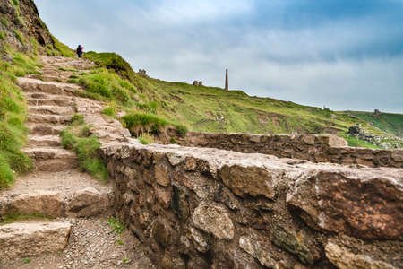 Chimneys and other disused mining buildings from Cornish tin mining industrial past,seen on...