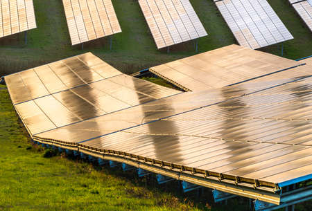 Solar energy creation,the Sun giving alternative,green,environmentally friendly eco power and sustainable energy to many angled solar panels, at a rural site,south of England.Golden sunset,blue sky.の写真素材