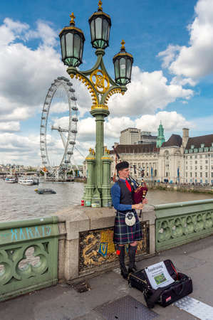 London,England,UK-August 21 2019: A young Scotsman in traditional dress, plays bagpipes for passers-by ,on one of London's most iconic bridges,to raise funds for the World Pipe Band Championships.のeditorial素材