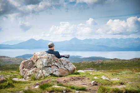 Applecross peninsula,Highlands of Scotland,UK-July 28 2022: A traveler and hiker,enjoys the mid summer views,from the top of the high mountain pass,overlooking beautiful Scottish scenery.のeditorial素材