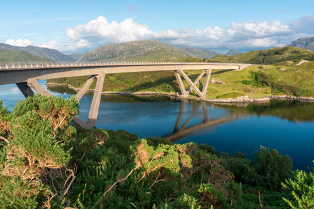 Distinctive modern curved,winding concrete box girder bridge,crossing the Loch a' ChÃ irn BhÃ in in Sutherland,.Pre sunset summer sunlight,blue sky and smooth water surface,beautiful green landscape.の写真素材
