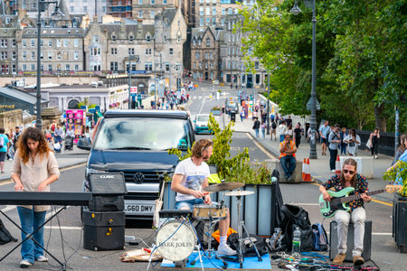 Edinburgh,Scotland-July 30 2022:The Dark Jokes group,play in the middle of the main road runnin past the rail station,temporarily closed during the Fringe Festival on a busy,warm sunny afternoon.のeditorial素材