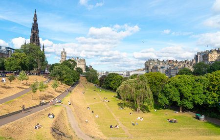 Edinburgh,Scotland-July 30 2022:During the summer Fringe Festival season,many people sit and relax on the sun kissed grass,near Scott Monument,as they enjoy the rare, warm sunny Scottish weather.のeditorial素材