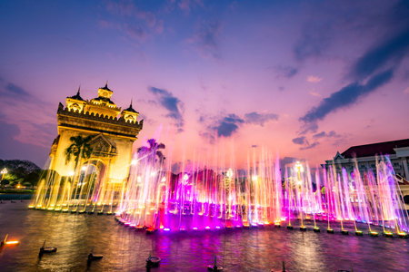 Beautiful,colorful light and fountain water display,synchronized with patriotic Lao music from nearby speakers,the Patuxay War memorial illuminated in the background.Performed every day,at dusk.の写真素材